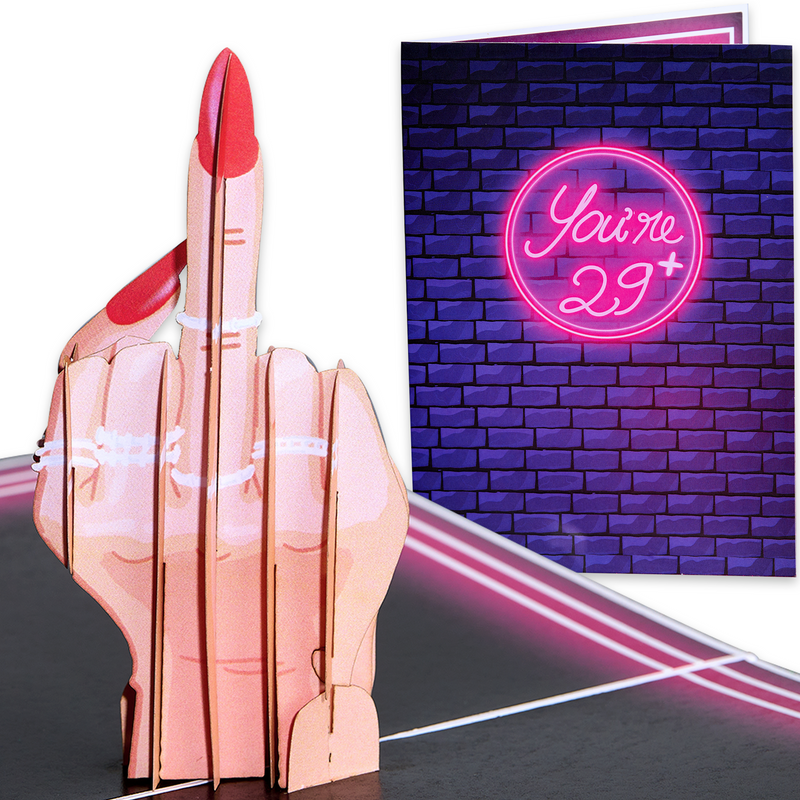 A pop-up card featuring a 3D hand with painted nails giving the middle finger, paired with a cover showing a neon sign reading You're 29+ against a brick wall. The design is bold, humorous, and playful for a cheeky birthday greeting.