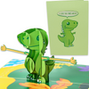 A pop-up card featuring a 3D green dinosaur with its arms outstretched, set against a colorful background. The matching green cover shows a cartoon dinosaur saying, I love you this much! creating a cute and affectionate theme.