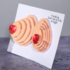 A humorous pop-up card with 3D breasts featuring red glittery hearts as nipples. The inside text reads, I would say heart but my boobs are bigger.Confetti is scattered around the card, emphasizing the playful and cheeky tone