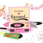 A pop-up greeting card designed as a pink record player, featuring a spinning vinyl that reads "I Love You So Much." The card includes musical notes and romantic details, creating a nostalgic and heartfelt gift.