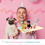 A smiling woman in a party hat holds a pug wearing a birthday hat alongside a pop-up card featuring three playful dogs. The card plays "Happy Birthday" in adorable barks, adding a fun and celebratory touch.