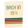 A cream-colored card cover with the text Back in 1974 in retro-style font, featuring multicolored horizontal stripes in blue, red, and yellow at the bottom, evoking a vintage 70s aesthetic.