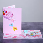 A playful greeting card with a pink cover featuring candy hearts with the text Let's Get Naked. The inside is filled with more candy hearts with flirty messages like Strip Tease and Sensual Massage, creating a fun and cheeky vibe.