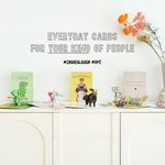 A collection of colorful and humorous pop-up greeting cards displayed on a white cabinet, with the slogan 'Everyday Cards for Your Kind of People' above them. Hashtags #ShareALaugh and #DPC are also featured, along with a vase of flowers
